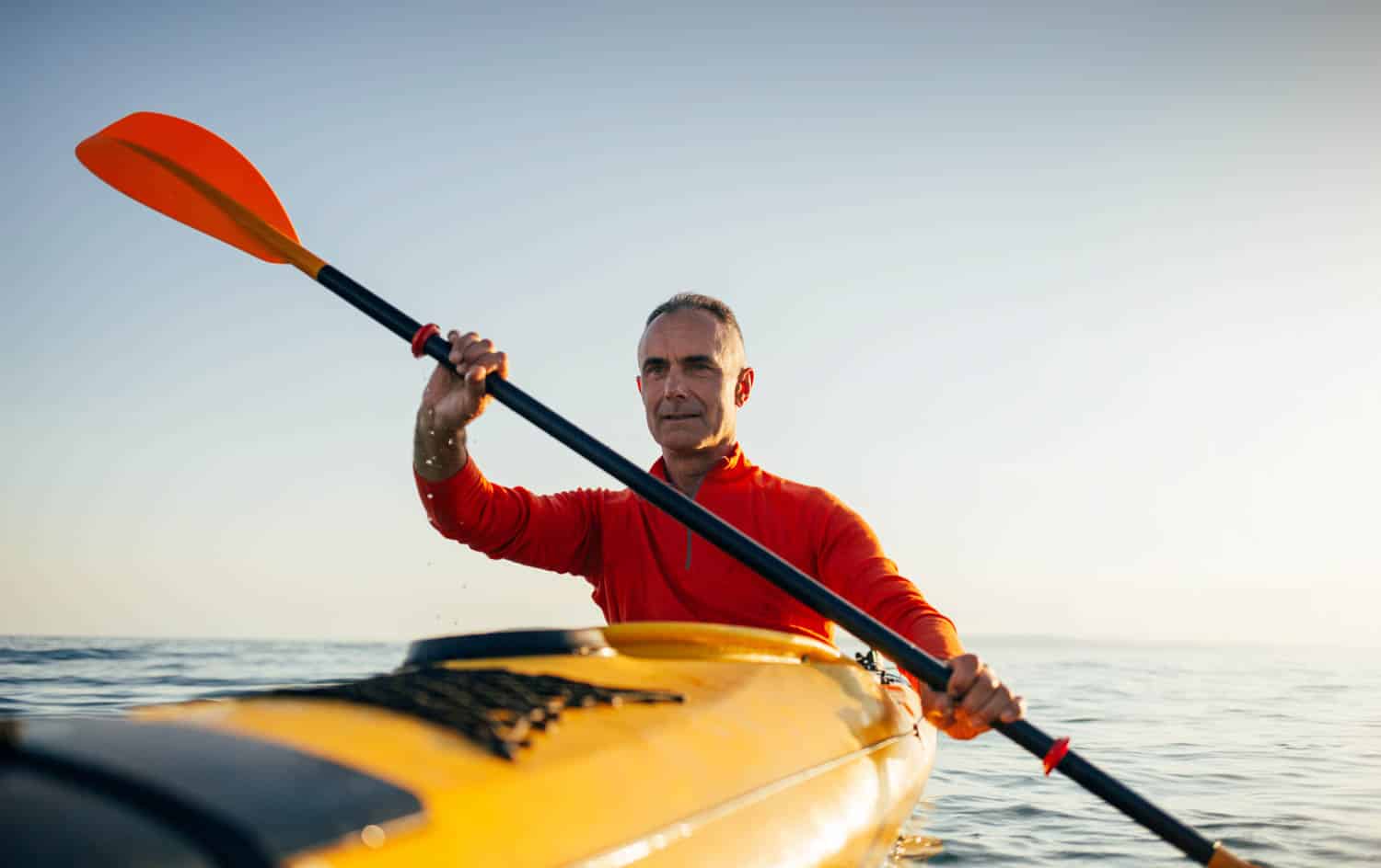 Active senior man paddling kayak